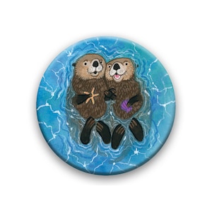 May include: Two brown and black sea otters are floating on their backs in a blue and white watercolor painting. The otters are holding a starfish and a purple shell.