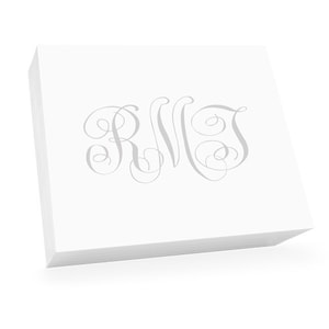 May include: A stack of white notepads with a silver monogram of the letters "RWT" in a cursive script.