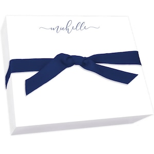 May include: A stack of white notepad paper with a navy blue ribbon tied around it. The notepad has the name "michelle" written in cursive on the front.