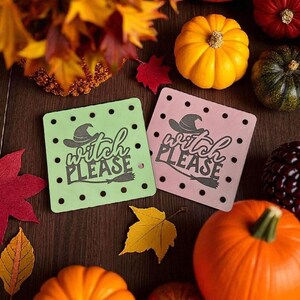 May include: A fall-themed arrangement featuring pumpkins in various sizes and colors, including orange, yellow, and green. Two square coasters, one green and one pink, display the text "Witch Please" with a witch hat and broom design. Autumn leaves add to the seasonal decor.
