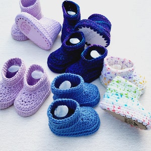 May include: A collection of crocheted baby booties in various colors, including purple, blue, and white. The booties are made with different stitch patterns and have a variety of textures.