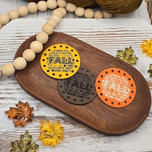 May include: Three circular leather tags with pre-punched holes around the edges. The tags are yellow, brown, and orange, each featuring the text FALL, PUMPKIN SPICE, SWEATER WEATHER, HAY RIDES, COZY, FLANNELS, BLESSED APPLE CIDER, and GIVING THANKS.