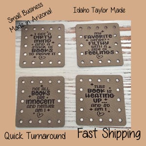 May include: Four square taupe leather patches with rounded corners and pre-punched holes along the edges. Each patch features dark brown engraved text with book-themed quotes, small star accents, and a heart symbol at the bottom of each design.