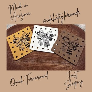 May include: Three square coasters with bow designs. One is mustard yellow, one is white, and one is brown. Each coaster has a bow design with black and white patterns and small holes around the edges. Text includes "Made in Arizona", "@idahotaylormade", "Quick Turnaround", and "Fast Shipping".