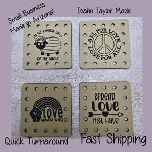 May include: Four square wooden coasters with various designs and text. One coaster features a sheep graphic and the text "I'm the rainbow sheep of the family." Other coasters have peace symbols, rainbows, and the phrases "Love always wins" and "Spread love not hate."