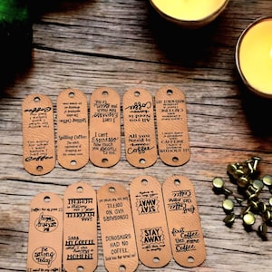 May include: Ten brown leather gift tags with coffee-themed sayings. The tags are decorated with black ink and feature sayings like "I can't Espresso how much you Bean to me" and "All you need is Coffee".