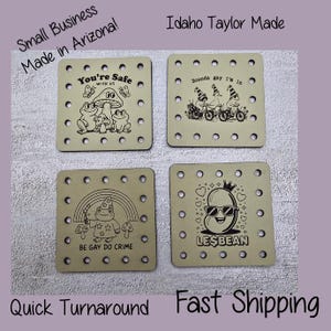 May include: Four square wooden coasters with various black and white illustrations and text. Designs include frogs, gnomes, a bean with sunglasses, and the phrases "You're Safe With Us", "Sounds gay I'm in", "Be Gay Do Crime", and "Lesbean".