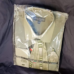 Op de afbeelding: Een nieuw, ongedragen, lichtgroen overhemd en stropdas set, verpakt in een doorzichtige plastic zak. Het overhemd heeft een puntkraag en de merknaam "DANIEL ELLISSA" is zichtbaar. De stropdas heeft een gestreept patroon in groen- en wittinten.