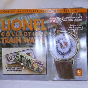 以下が含まれることがあります： オリジナルパッケージに入ったLionel Collectible Trainウォッチ。箱には、白い文字盤、茶色のレザーストラップを備えたゴールドトーンの時計が描かれており、Officially Licensed Collector's Edition、Featuring Motion & Real Train Sounds、Trains Actually Movesなどのテキストが記載されています。小さな挿入画像には、装飾的な金属製の缶に入った時計が写っています。
