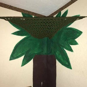 May include: A green painted tree mural on a wall with a brown crocheted hammock hanging from the ceiling.