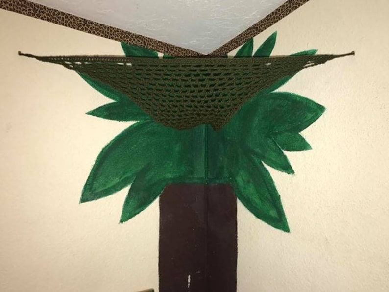 May include: A green painted tree mural on a wall with a brown crocheted hammock hanging from the ceiling.