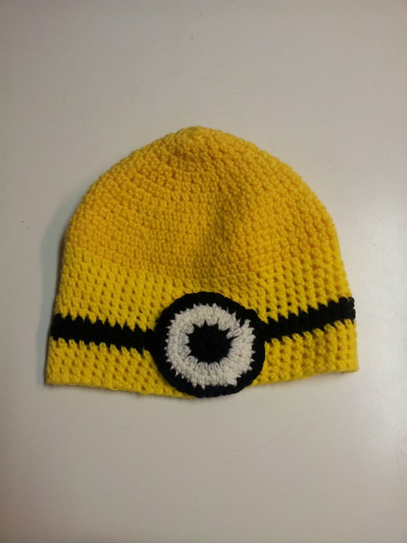 May include: Yellow crocheted hat with a black and white eye design.