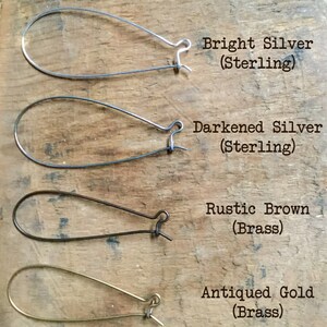 May include: Four different earring styles: bright silver, darkened silver, rustic brown, and antiqued gold. Each earring is a simple, teardrop-shaped hoop.