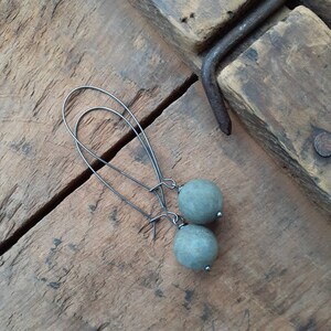 May include: A pair of silver dangle earrings with round, gray stone beads.