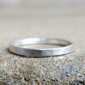 May include: A simple silver band ring with a hammered finish.