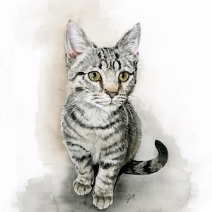 May include: A watercolor painting of a grey tabby kitten with dark stripes, pointed ears, and light green eyes. The kitten is sitting in a forward-facing position against a soft, neutral-toned wash background. The artist's initials are visible.