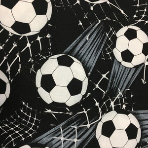 May include: Black and white fabric with a repeating pattern of footballs and a stylised net design.