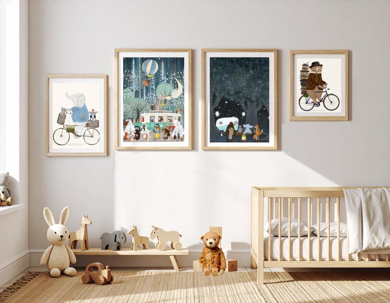 May include: Four framed wall art prints featuring whimsical animal illustrations, including an elephant on a bicycle, a forest camping scene with a camper van, a night scene with a campfire, and a bear riding a bicycle with a stack of books.