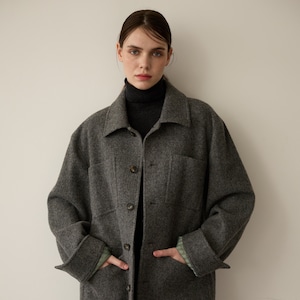 Op de afbeelding: Een grijs wollen jack met een kraag, lange mouwen en knoopsluiting. Het jack heeft twee grote zakken aan de voorkant en een losse pasvorm.