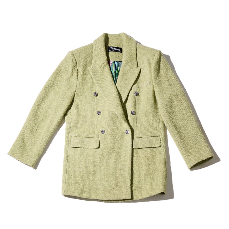 May include: A light green double-breasted blazer with silver buttons. The blazer has a textured fabric and a small label that says "Freaks" on the left side of the collar.