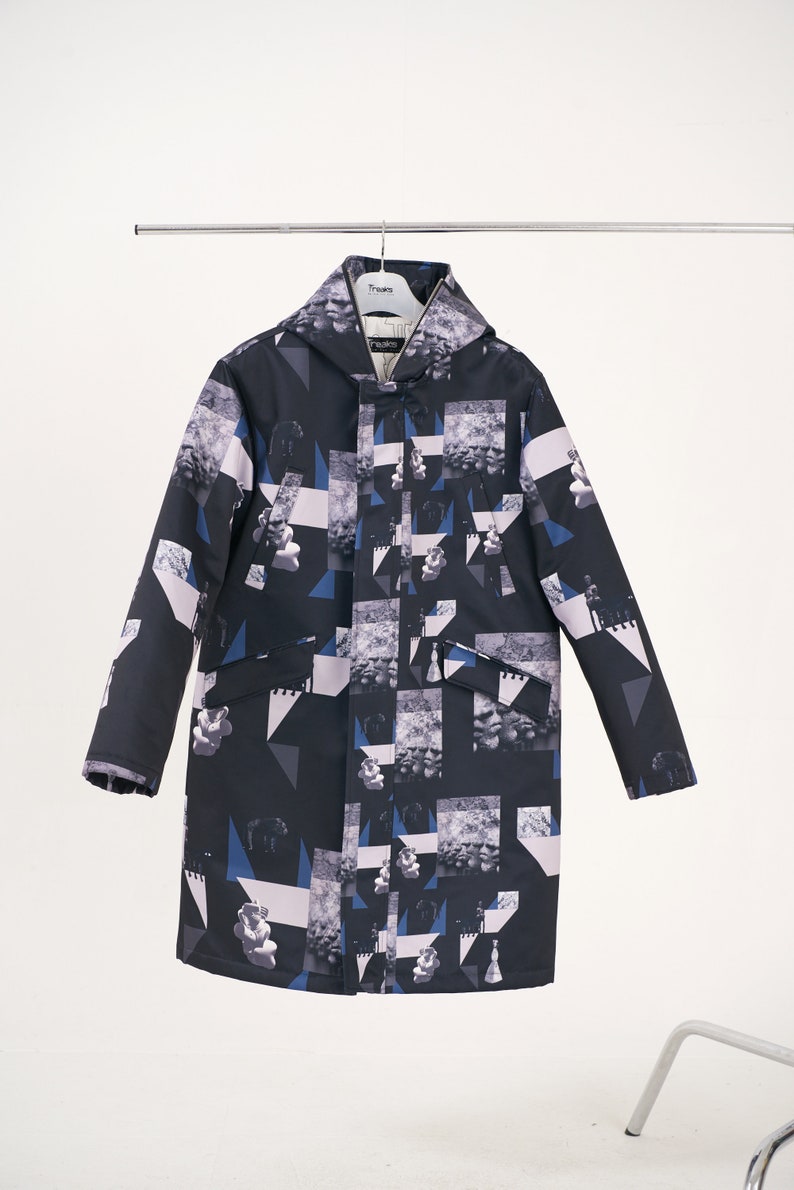 Puede incluir: Una chaqueta negra con capucha con un estampado geom&eacute;trico y abstracto en tonos azules, blancos y grises. La chaqueta tiene una cremallera y dos bolsillos.