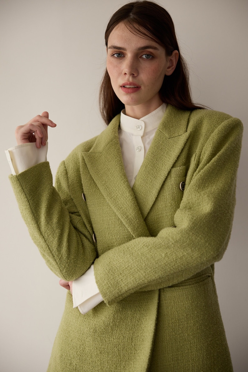 May include: A green double-breasted blazer with a white collared shirt underneath.