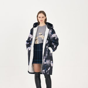 Puede incluir: Una mujer lleva un abrigo largo de estampado negro y blanco con capucha, un jersey gris con un peque&ntilde;o gr&aacute;fico de un perro, una falda de cuadros azules y negros y botas negras hasta el muslo.