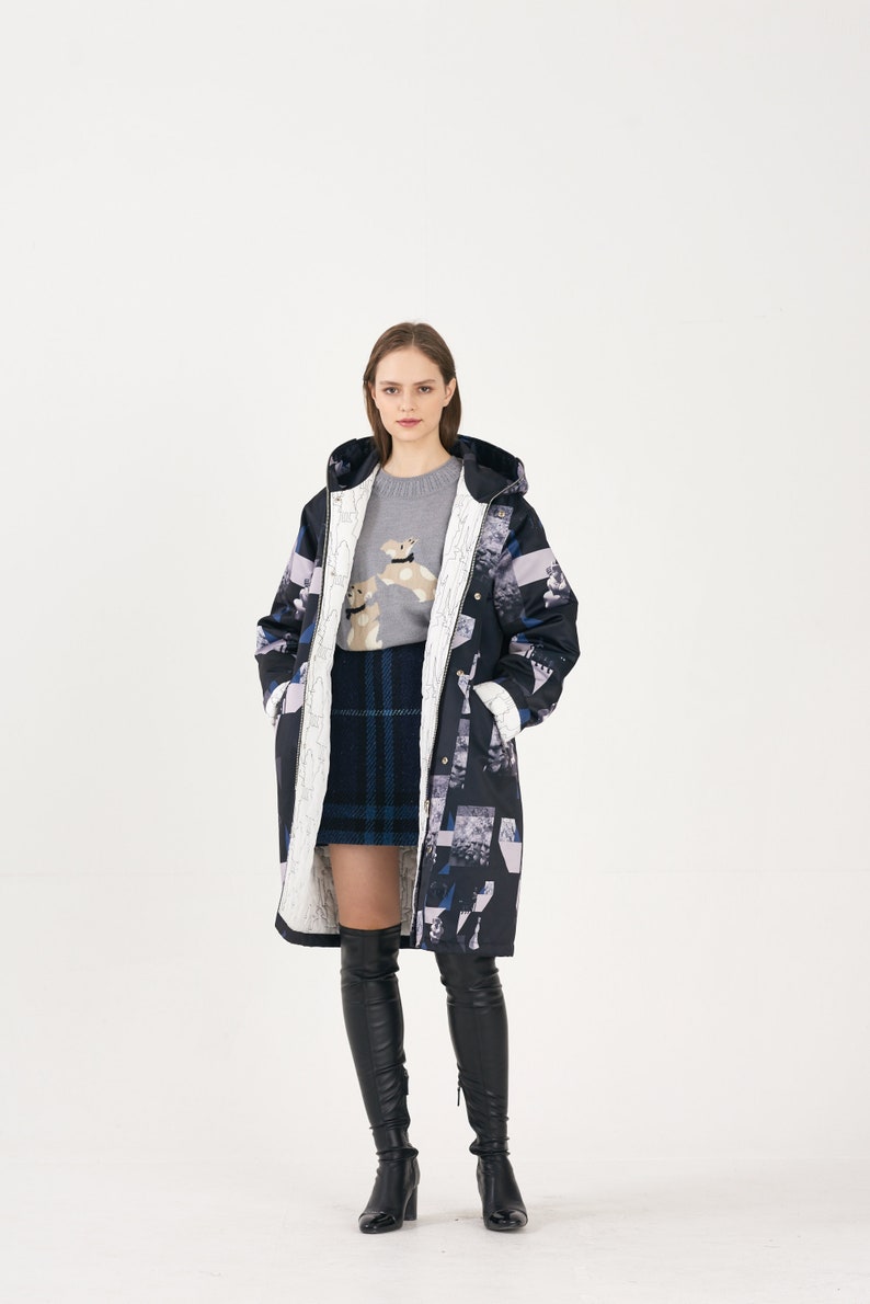 Puede incluir: Una mujer lleva un abrigo largo de estampado negro y blanco con capucha, un jersey gris con un peque&ntilde;o gr&aacute;fico de un perro, una falda de cuadros azules y negros y botas negras hasta el muslo.