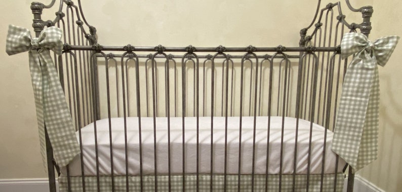 Pu&ograve; includere: Una culla in stile vintage con struttura in metallo. La culla presenta un materasso bianco e una gonna e fiocchi a quadretti verdi e bianchi. Il design della culla &egrave; classico ed elegante, adatta a una cameretta.