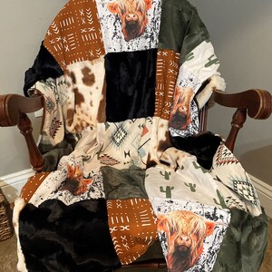 May include: A patchwork blanket draped over a wooden chair. The blanket features a variety of patterns, including cowhide, tribal designs, and a Highland cow face. Colors include brown, black, white, and green.