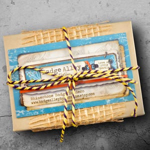 a package wrapped in a yellow and blue twine, tied with a yellow string, and placed on a concrete surface.