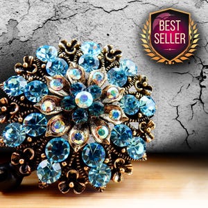 a decorative piece of jewelry with blue and gold elements, including a large blue gemstone surrounded by smaller blue gemstones. The background is a cracked concrete wall with a "Best Seller" sign in the top right corner.