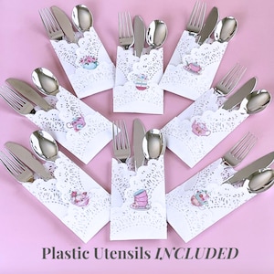 May include: Arrangement of silverware sets, each including a fork, knife, and spoon, presented in white lace doilies. Each doily is decorated with a small teacup illustration. The text "Plastic Utensils INCLUDED" is at the bottom.