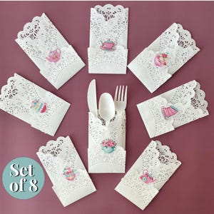 May include: Set of eight white doilies with a delicate lace pattern and a teacup design. Each doily has a different teacup design with floral accents. The doilies are perfect for adding a touch of elegance to any tea party or special occasion.