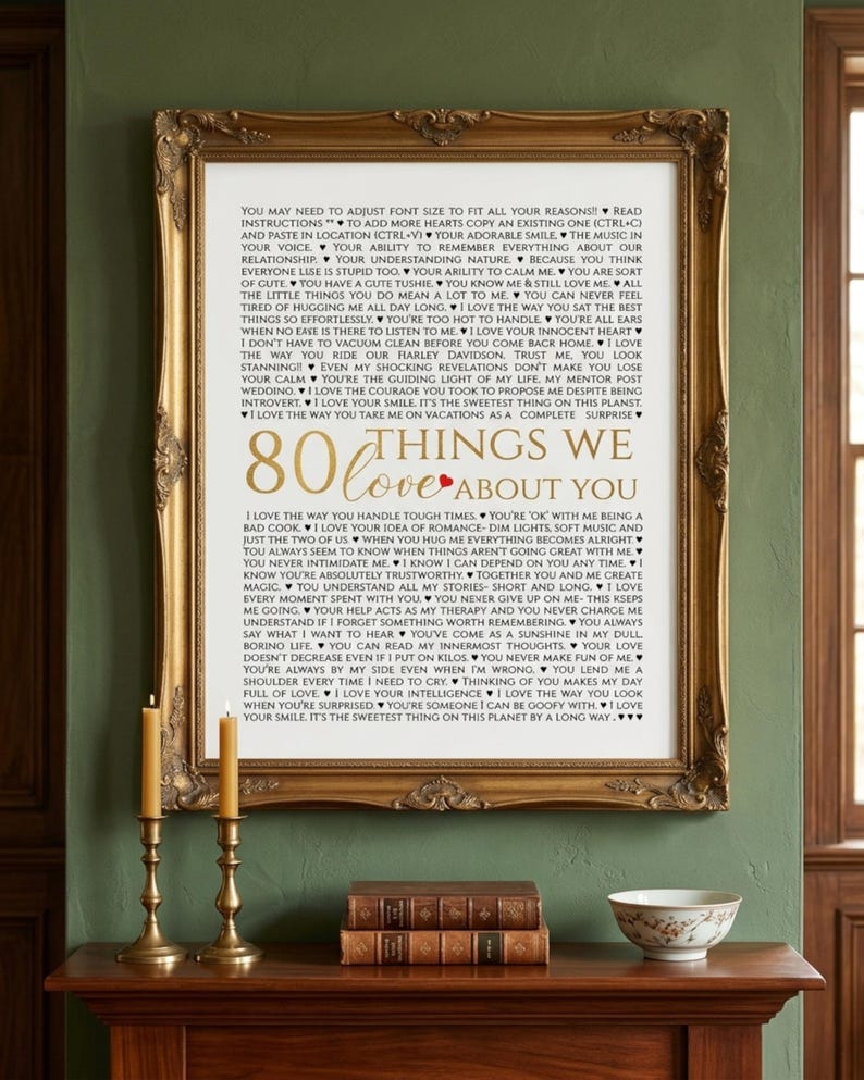 K&ouml;nnte beinhalten: Ein gerahmter Kunstdruck mit dem Titel 80 THINGS WE LOVE ABOUT YOU, mit schwarzem Text auf wei&szlig;em Hintergrund und einem kleinen roten Herzen. Der verzierte goldene Rahmen umgibt die Liste der Gr&uuml;nde, die pers&ouml;nliche Nachrichten enth&auml;lt.