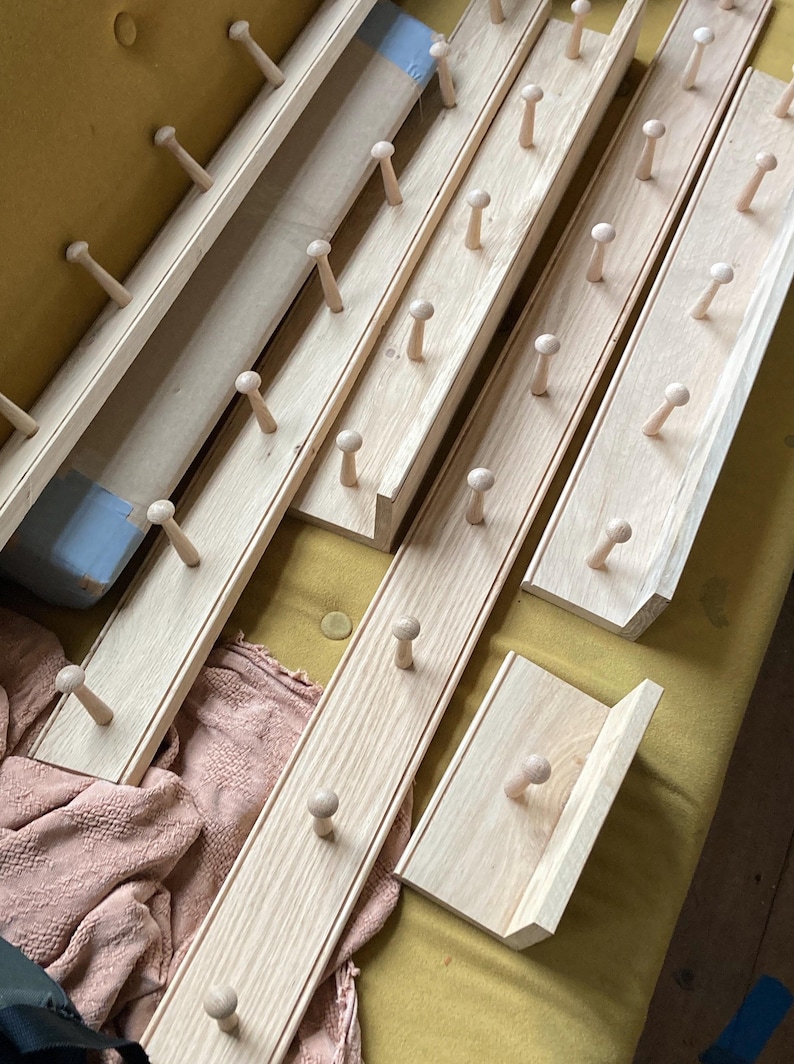 Puede incluir: Conjunto de seis percheros de madera con clavijas redondeadas. Los percheros son de madera clara y tienen un acabado natural.