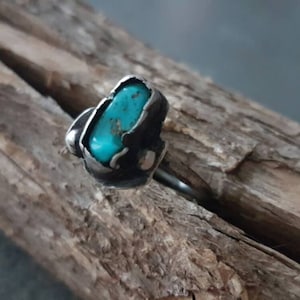 K&ouml;nnte beinhalten: Ein Silberring mit einem T&uuml;rkis-Stein, der in einer rauen, organischen Form gefasst ist. Der Stein hat eine leuchtende blaugr&uuml;ne Farbe.