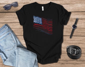 May include: Black t-shirt with a distressed American flag design. The flag features a blue square with white stars and red and white stripes. The shirt is shown with blue jeans, sunglasses, a watch, and a black belt.