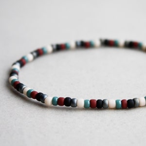 May include: A multi-colored beaded bracelet with black, white, red, and blue beads.