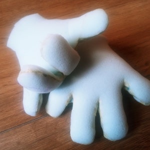 May include: A pair of white foam hand puppets with finger holes. The puppets have a textured surface and are designed to look like hands.