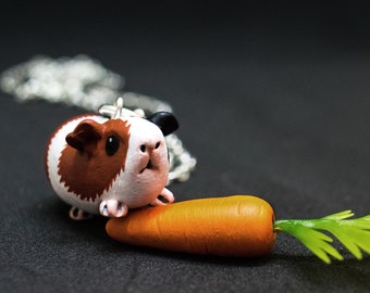 May include: A brown, white, and black guinea pig figurine wearing a silver chain necklace and holding a small orange carrot with green leaves. The figurine is made of polymer clay and is a cute and whimsical charm.