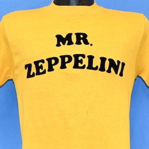 Camiseta amarela com letras flocadas e ferro de passar do Sr. Zeppelini dos anos 70, pequena