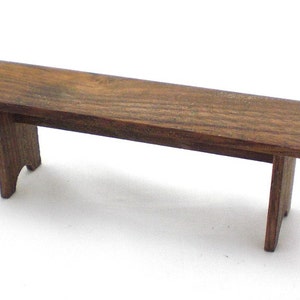 May include: A simple wooden bench with a brown stain. The bench has a rectangular top and two short legs on each end.