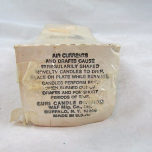 May include: A white box with black text explaining that air currents and drafts can cause irregularly shaped novelty candles to drip. The box also states that the candles perform best when burned out of drafts and for short periods of time. The box is labeled "Suni Candle Division, W&F Mig. Co., Inc., Buffalo, N.Y. 14206, Made in U.S.A."