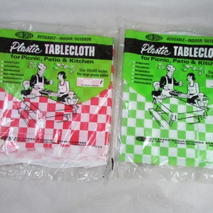 May include: Two packages of plastic tablecloths, one red and white checkered and one green and white checkered. Both packages feature a cartoon illustration of people having a picnic. The text on the packages reads "Reusable - Indoor/Outdoor Plastic Tablecloth for Picnic, Patio & Kitchen" and "Size - 84x40 Inches fits large picnic tables".