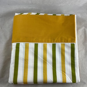 May include: Folded bedding set featuring a mustard yellow top section and a striped bottom section. The stripes alternate between white, olive green, and mustard yellow. The fabric appears to be cotton or a similar material.