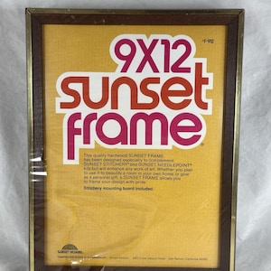 May include: A rectangular Sunset Frame with a dark brown wood border and a thin gold inner trim. The insert features the text 9X12 sunset frame, F-912, and descriptive product information on a yellow background, noting a stitchery mounting board is included.