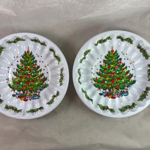 May include: Two white plastic Christmas-themed jelly moulds with a green Christmas tree design and red and gold baubles.