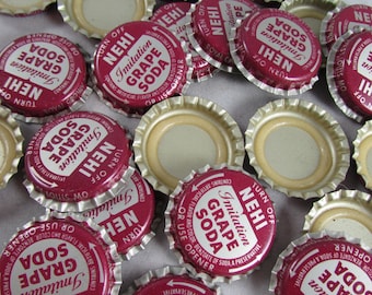 May include: A collection of vintage bottle caps for Nehi Grape Soda. The caps are red with white lettering and feature the brand's logo and slogan. Some caps are gold with a red band.