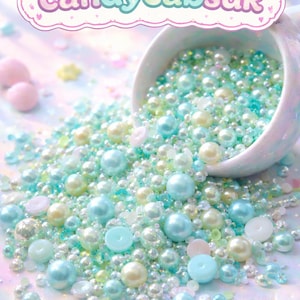 Peut inclure: Une tasse en céramique blanche déverse un assortiment de perles et de billes aux couleurs pastel. Les perles sont dans les tons de bleu, vert, jaune et rose. Le texte "candycabsuk" est au-dessus de la tasse dans une bannière rose et violette.